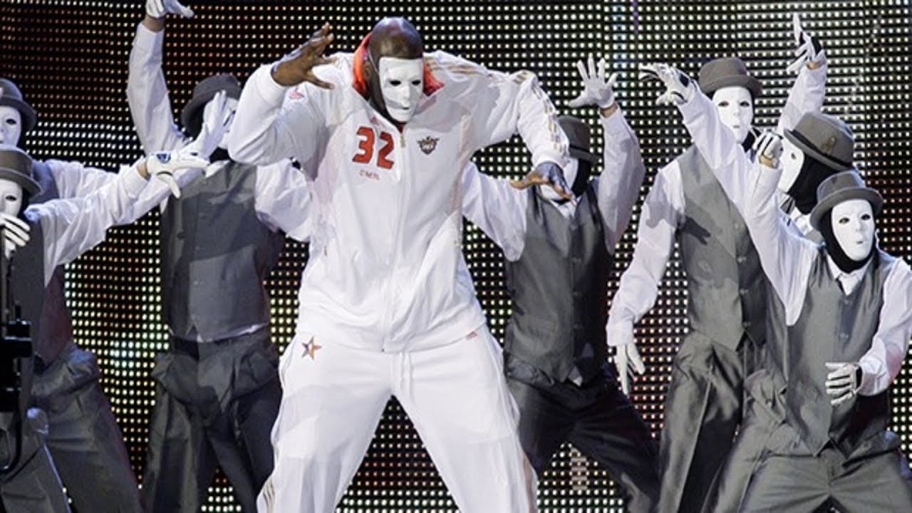 Shaq dancing in a dance crew with all crew members wearing white masks.