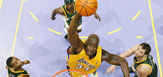 Shaq dunking a basketball over three opponents.