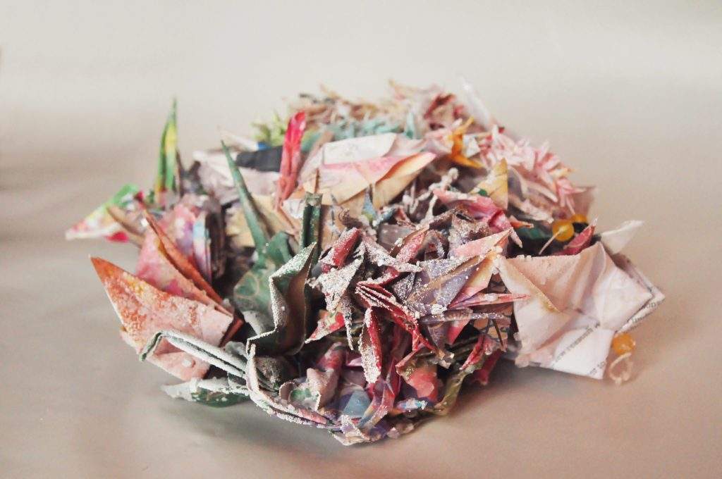 a pile of colofrul paper cranes with chrystals growing on them. 