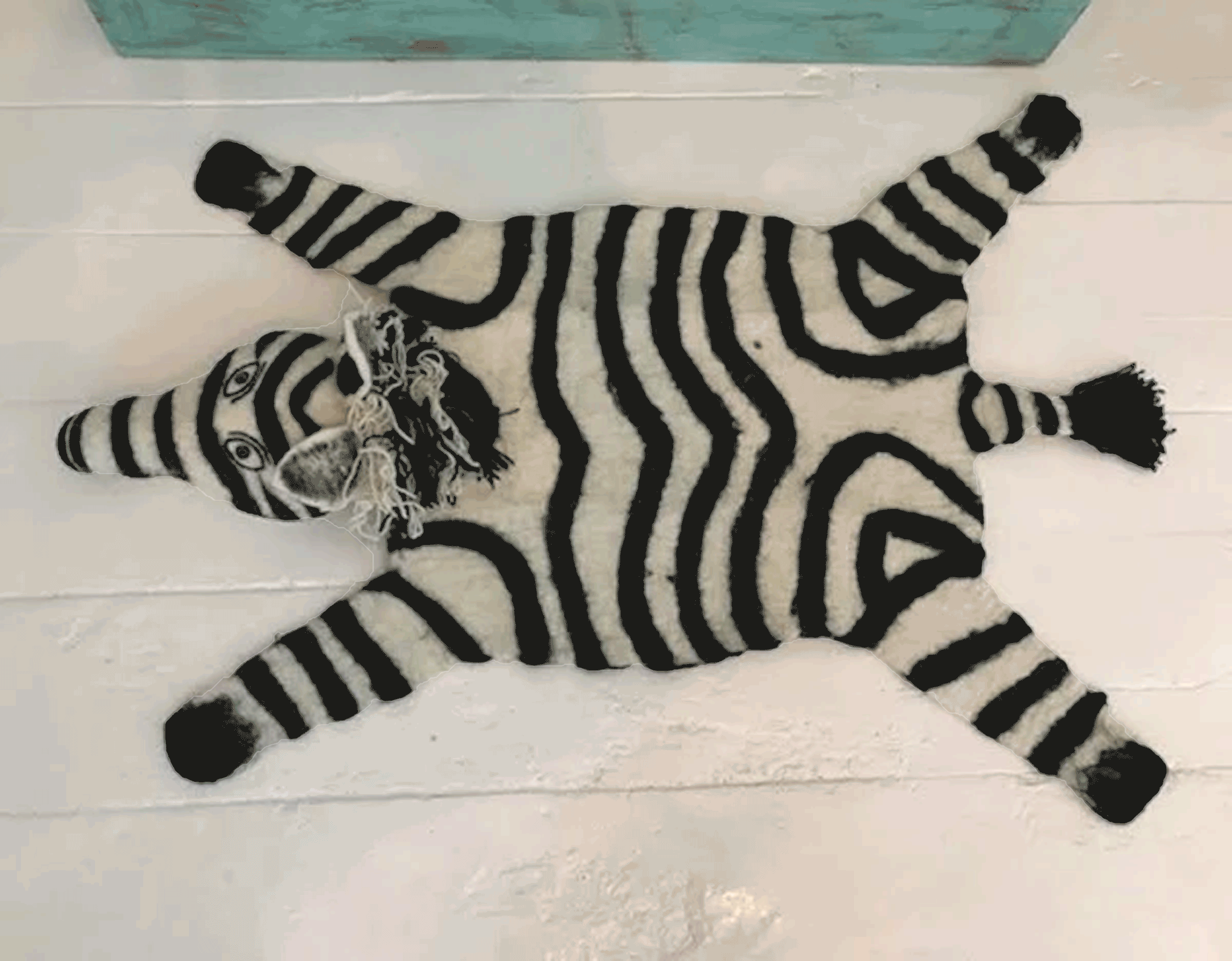 An image of a savanna dissolves to black transparency behind a
          top-down photo of a unique zebra-designed rug facing right. 