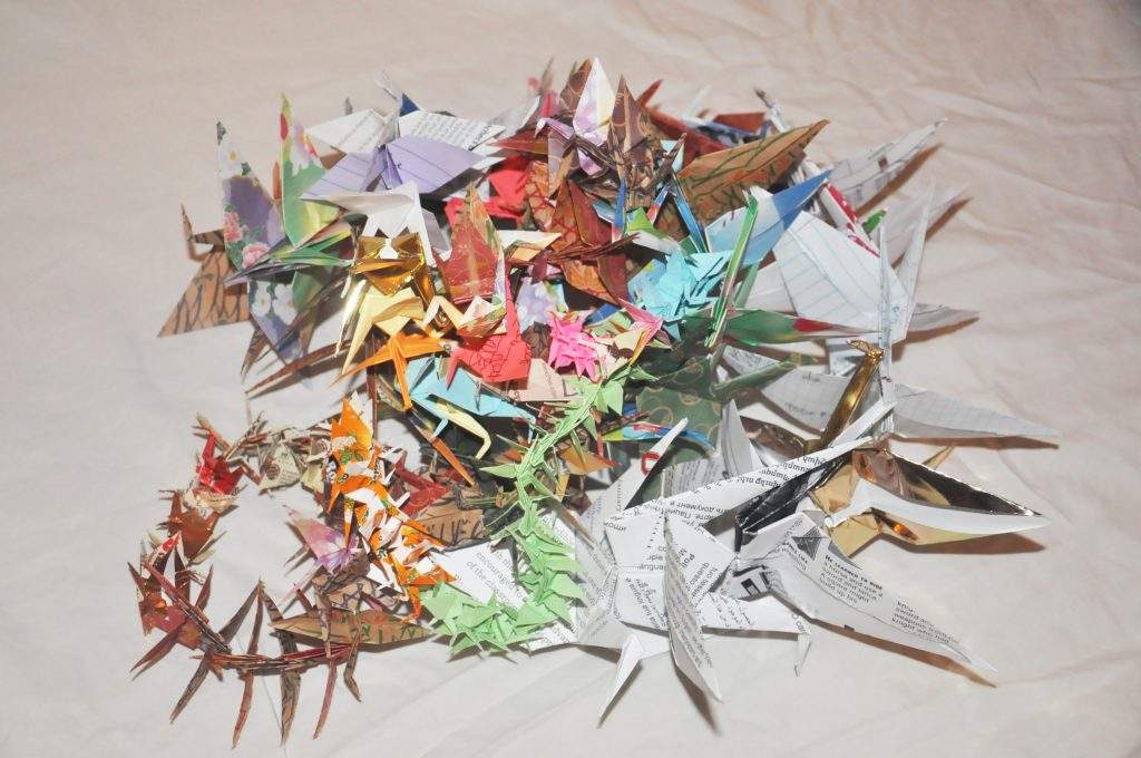 an asortmant of colorful spikey paper cranes in a sculptural pile on a white background. 