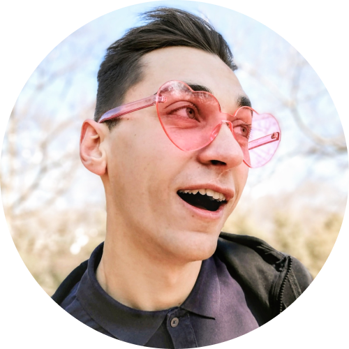 Photo of Gleb smiling and wearing pink heart-shaped glasses
